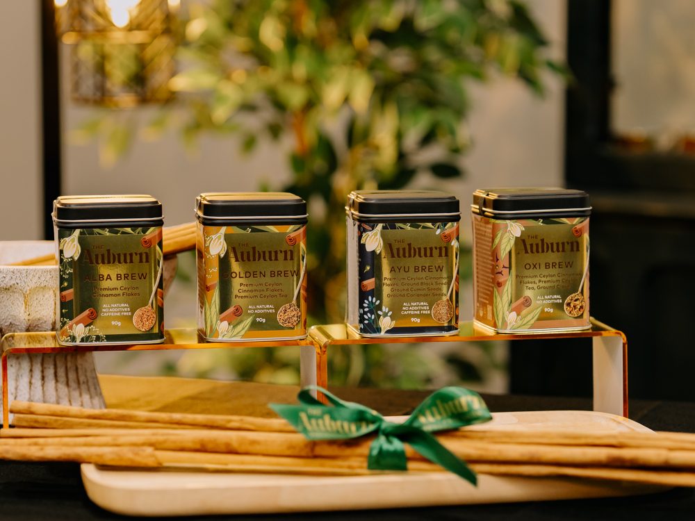 Alba, Golden, Ayu and Oxi Brew tins displayed on a gold stand