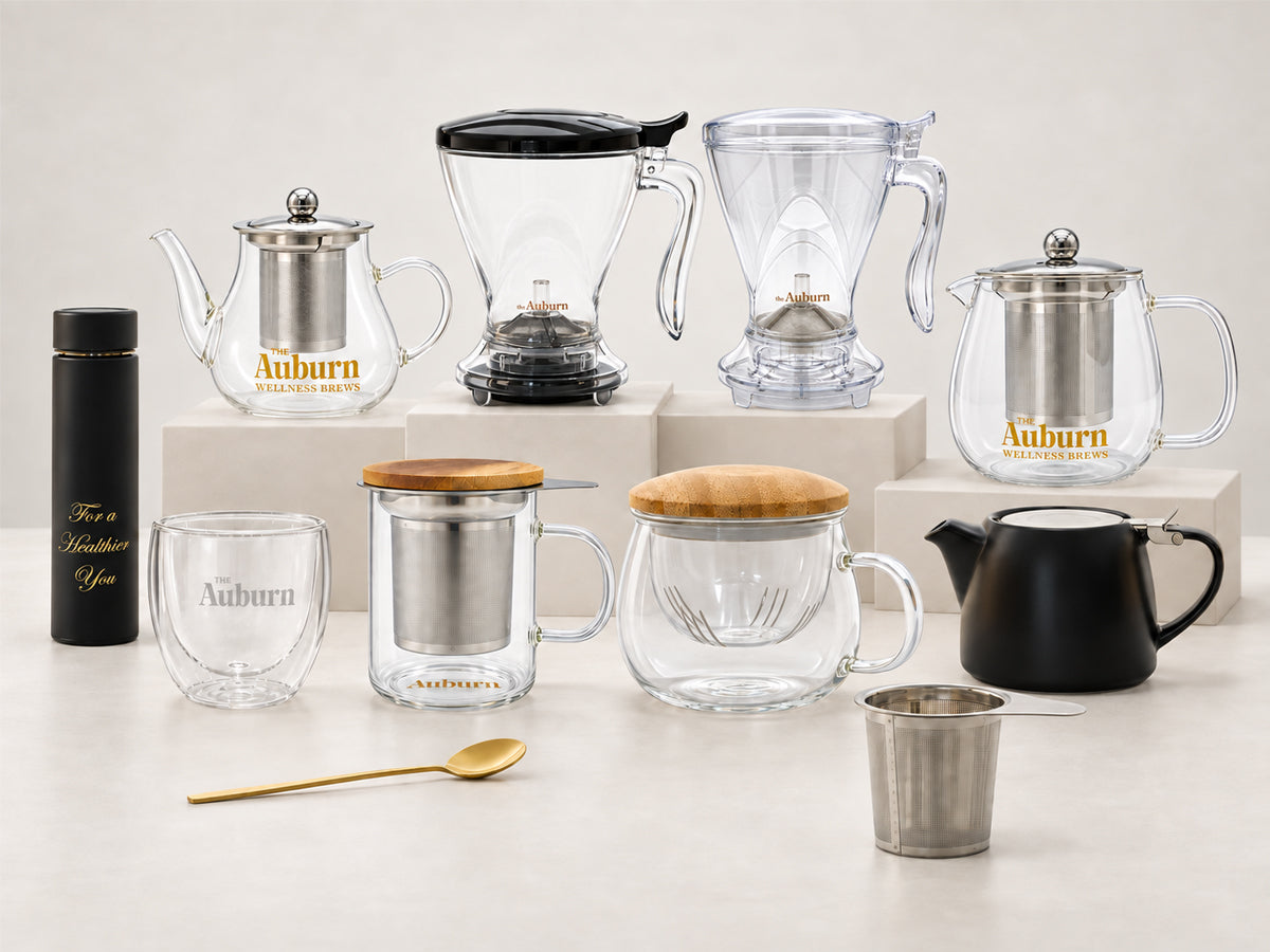 The Auburn Brew Maker Jug, glass mug with a wooden lid, stainless steel strainer, gold spoon and matte black teapot