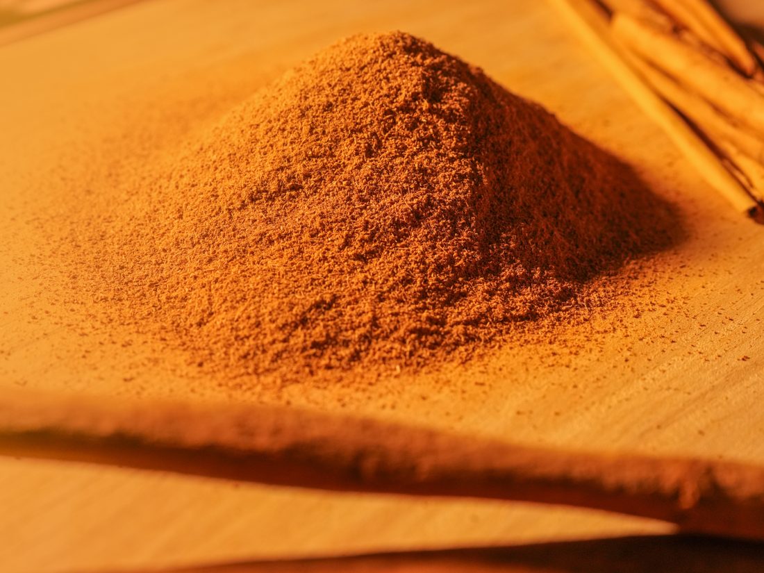 Ground Ceylon Cinnamon powder beside whole quills